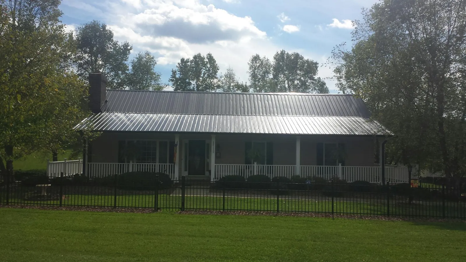 Gray metal roof on a brick ranch with a full width front porch — Gutter Guard Installation work by our crew in Ridgewood